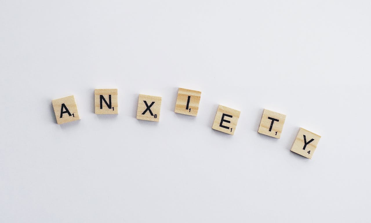 Wooden tiles on a white background spell anxiety, symbolizing mental health awareness.